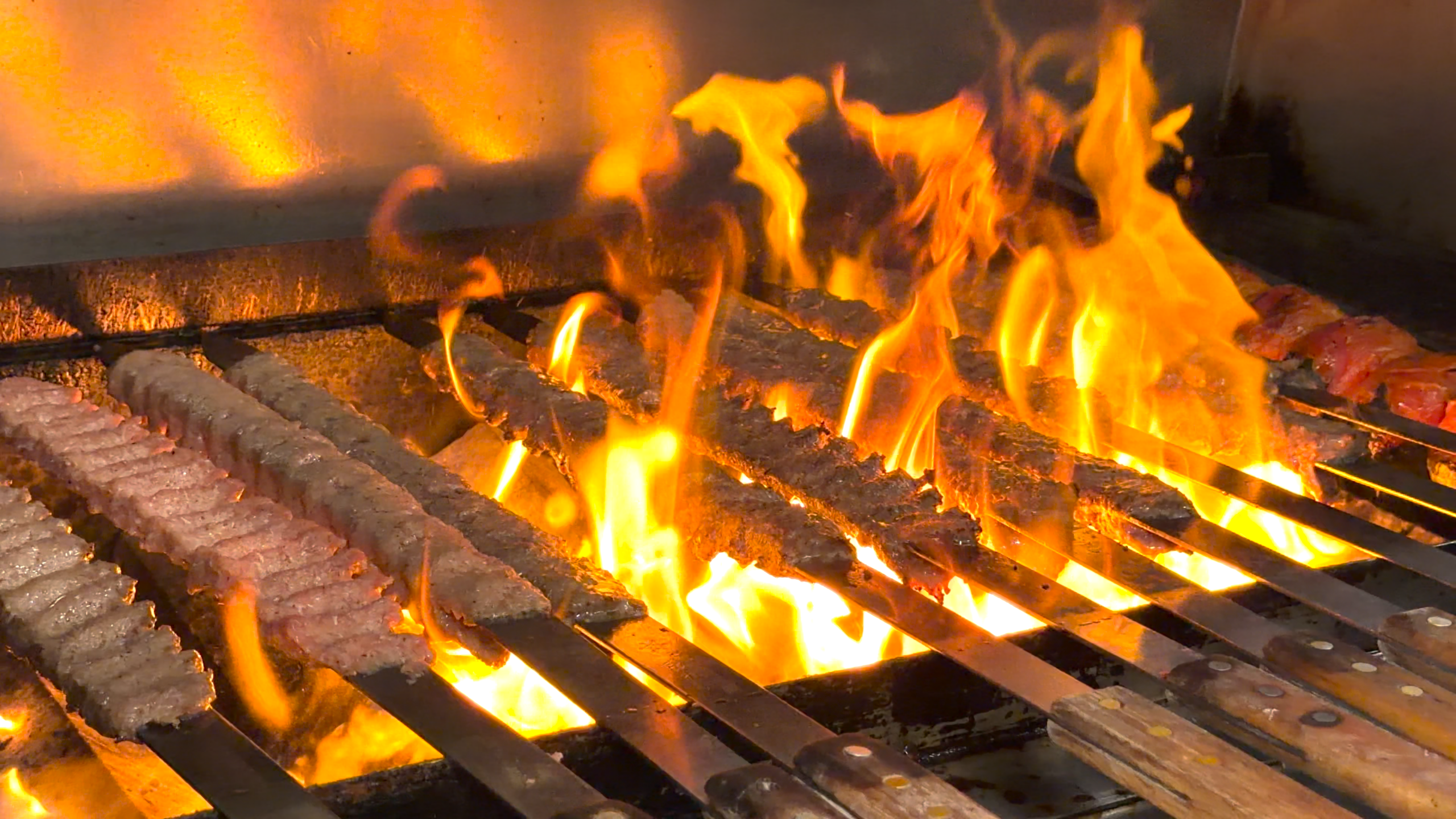 Beef kabobs grilling over an open flame at Bayshore Lounge in Newport Beach