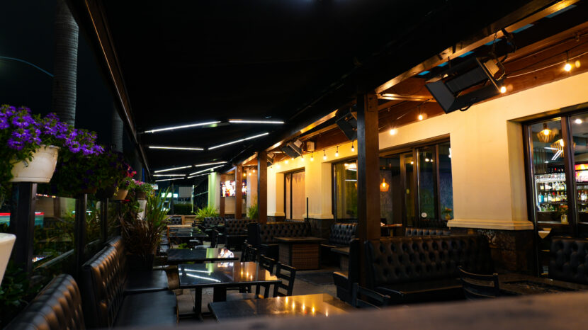 Bayshore Lounge outdoor patio dining area in Newport Beach with warm lighting and group seating.