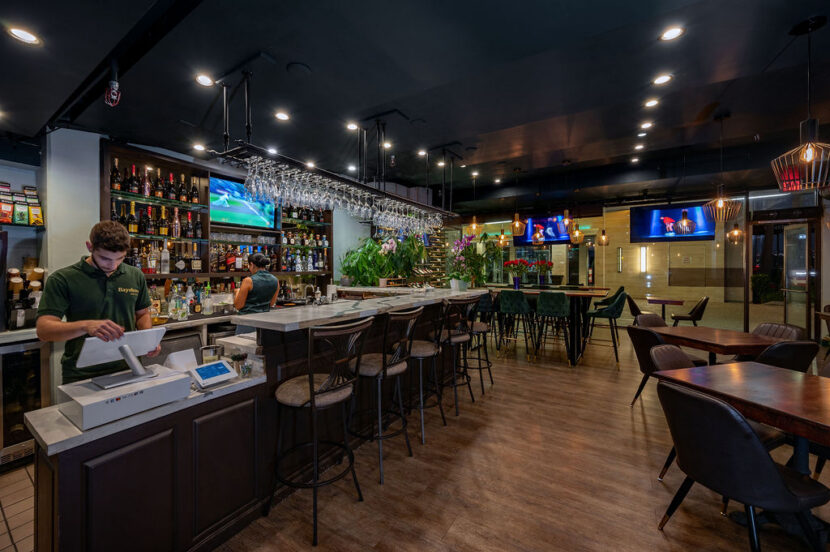 Bayshore Lounge bar and dining room with full bar seating, warm lighting, and restaurant tables in Newport Beach.